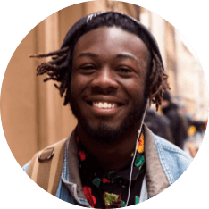 A smiling dark skinned man with dreadlocks